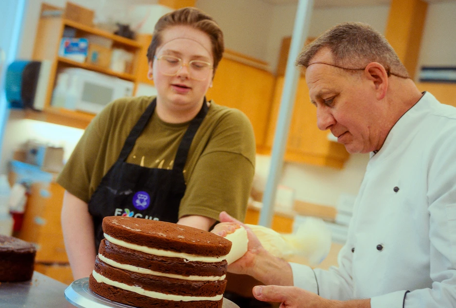 Chef Claude avec un élève, qui font un gâteau étagé