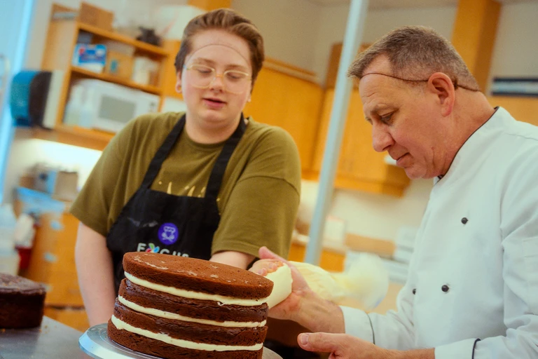 Chef Claude avec un élève, qui font un gâteau étagé